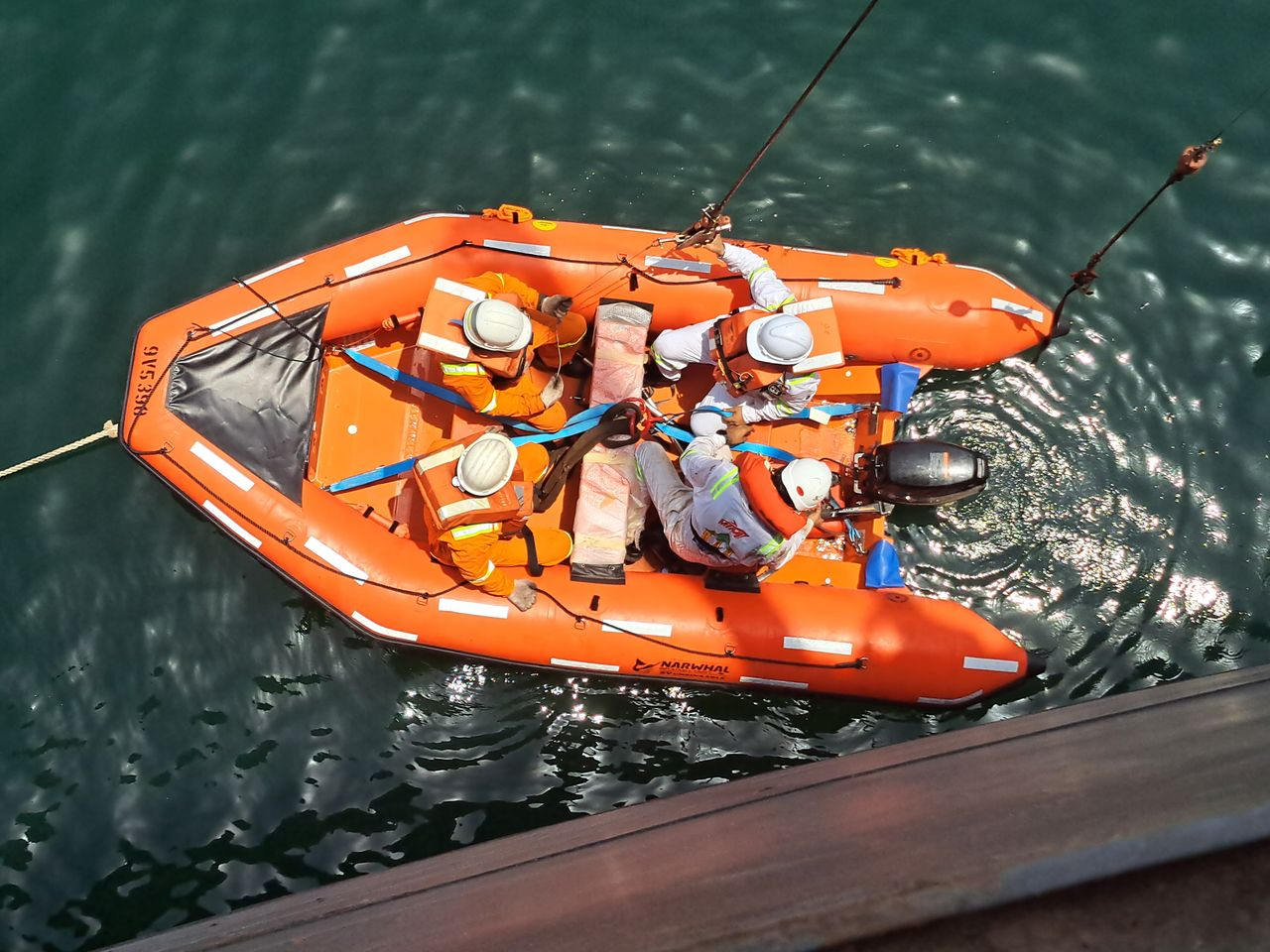 A group of people in a lifeboat conducting a rescue training drill on open water.